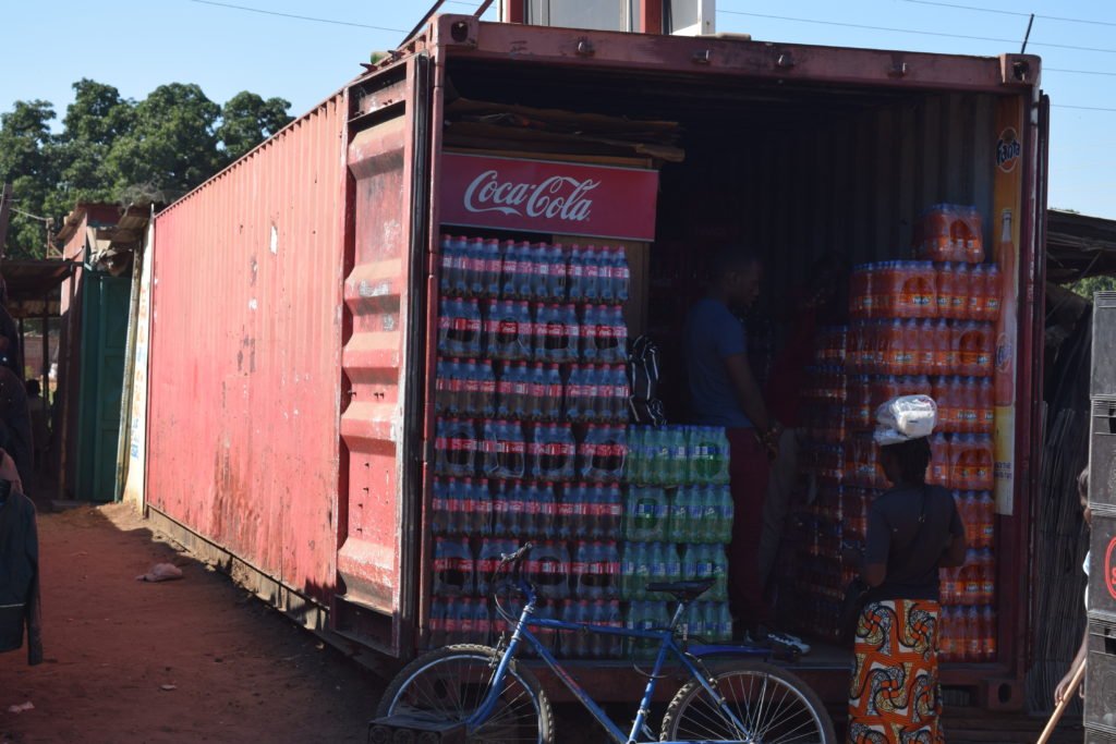 A guy selling fizzy drinks from the back of a container at Maramba Market
